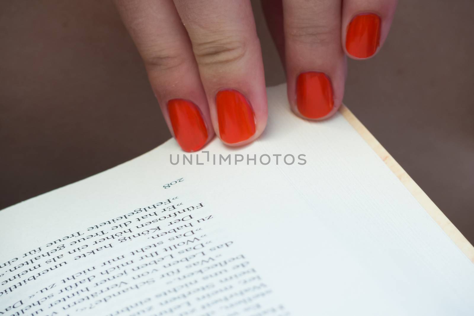 Changing page of book orange fingernails