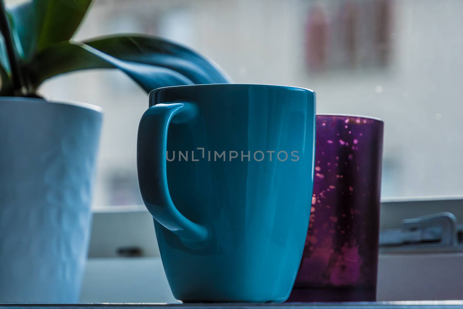 Bright blue cup standing on window board by MXW_Stock