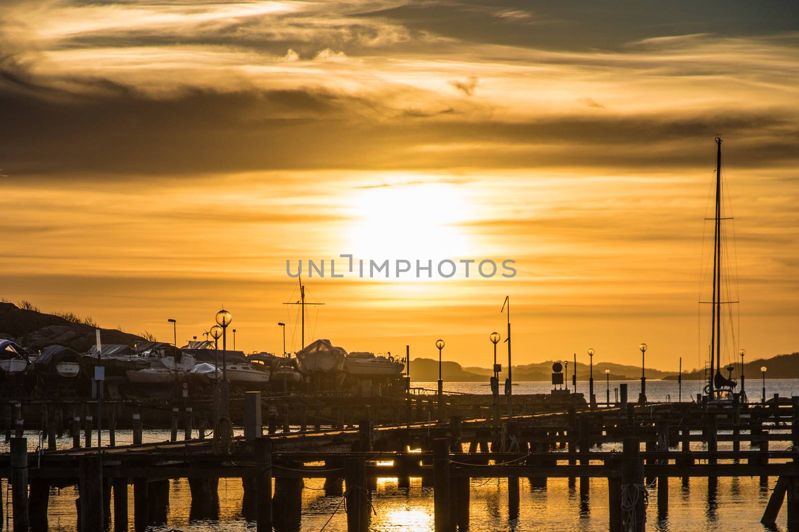 Orange and yellow sky above harbor port sunset boats by MXW_Stock