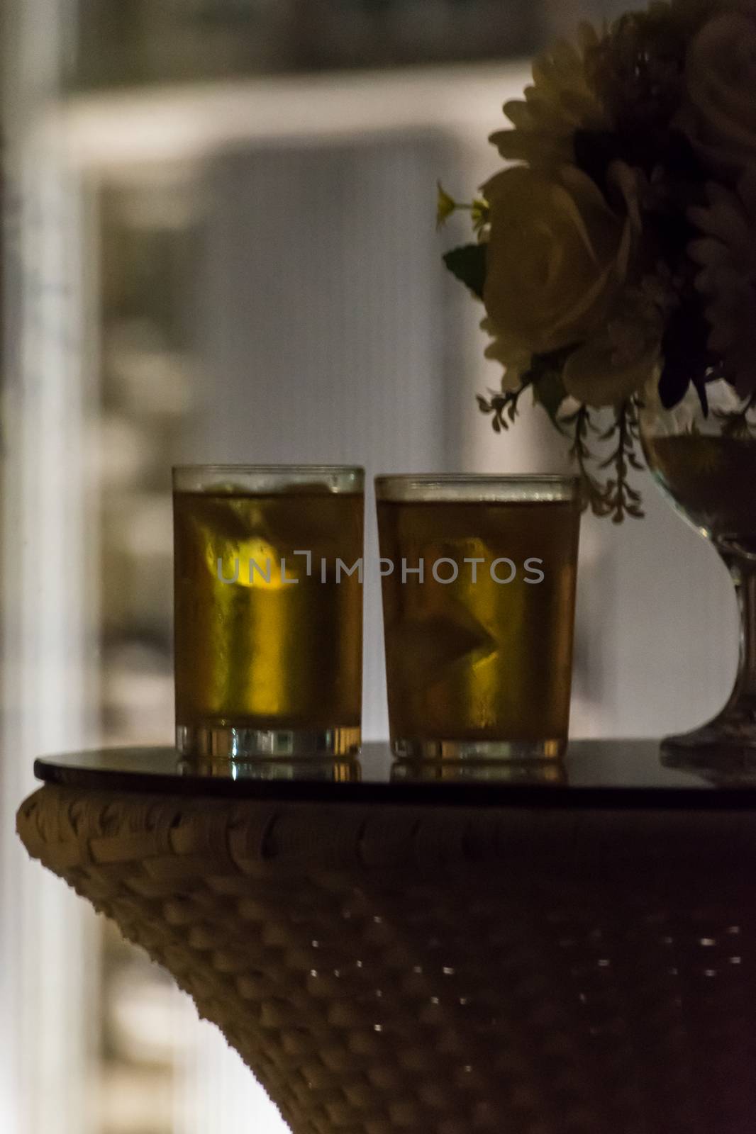Two ice cold drinks standing on table at night in front of windo by MXW_Stock
