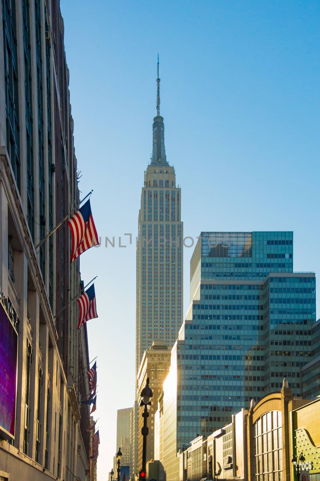 View of the Empire State Building during sunrise american flags by MXW_Stock