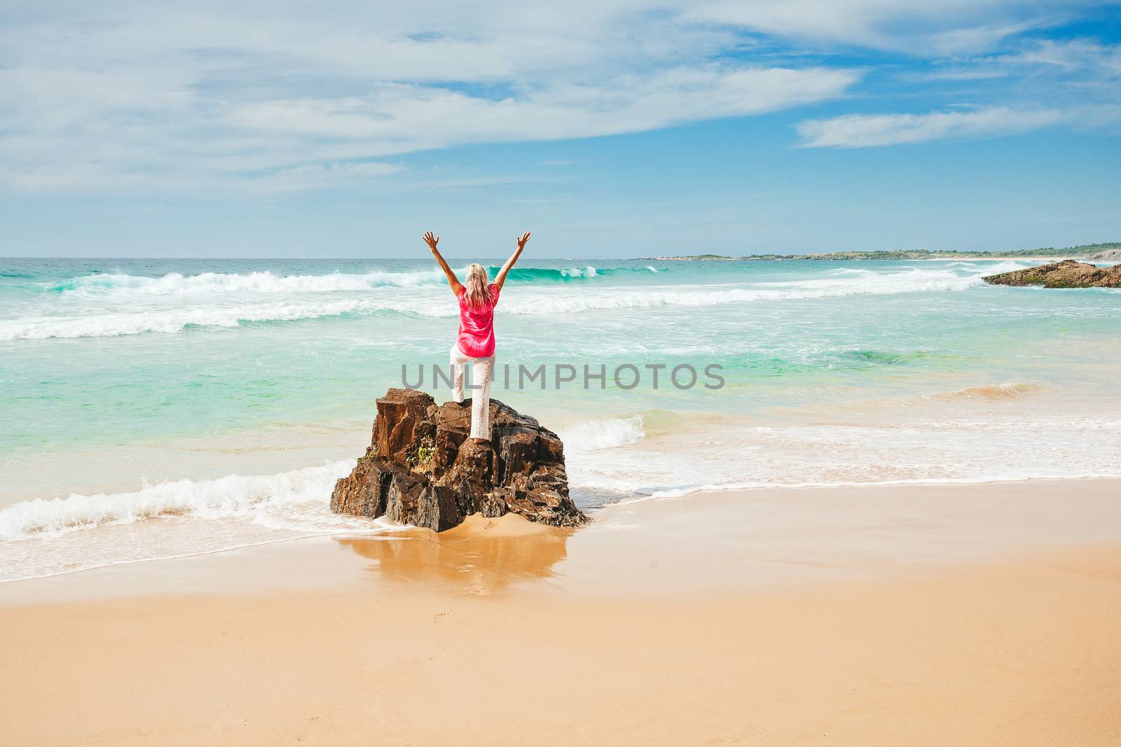 Woman wearing tie tied shirt standing on the sea shore on a beautiful sunny day.  Space for copy.
