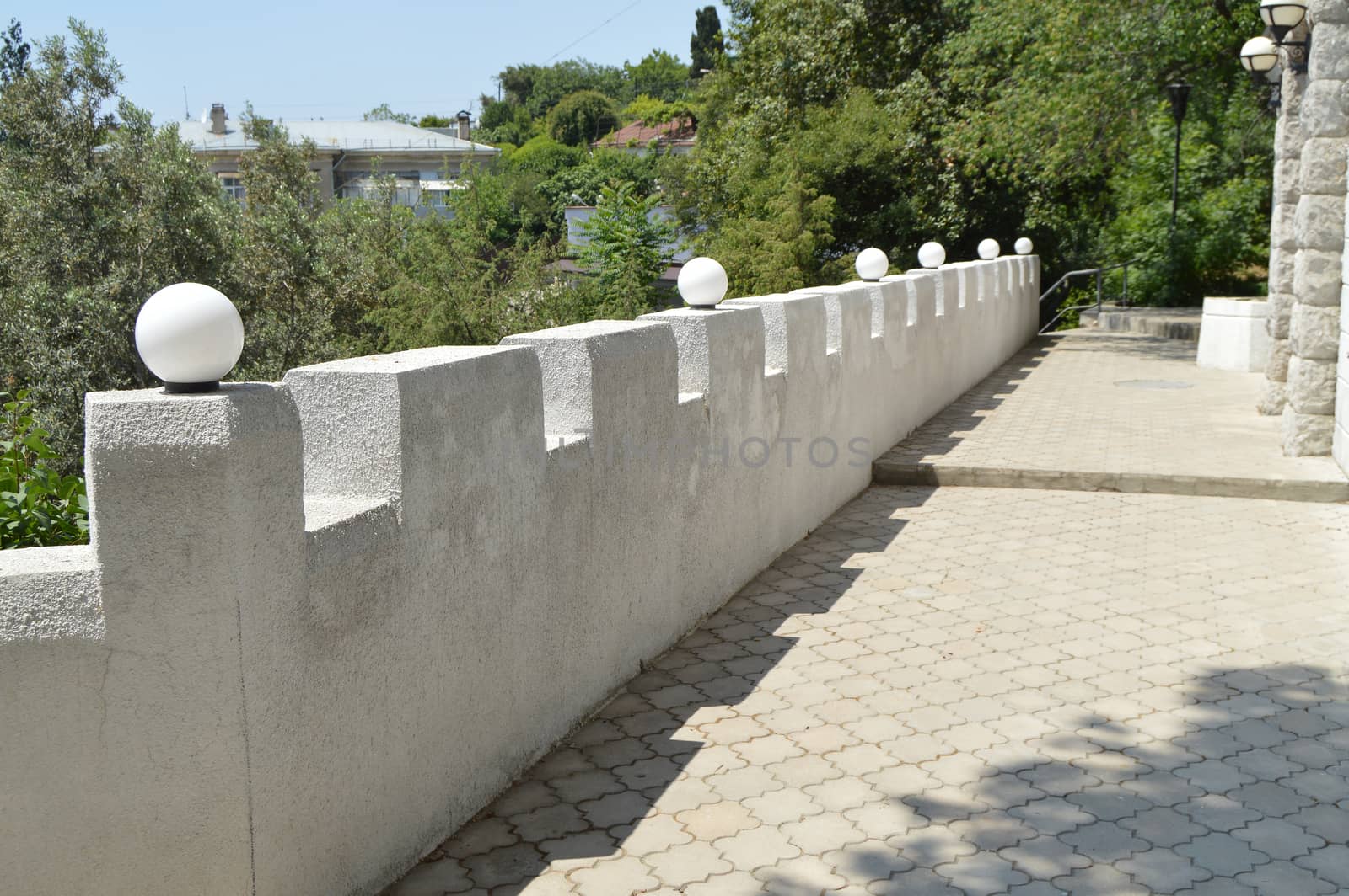 Beautiful view of the white stone fence terraces decorated with lanterns on a Sunny summer day.