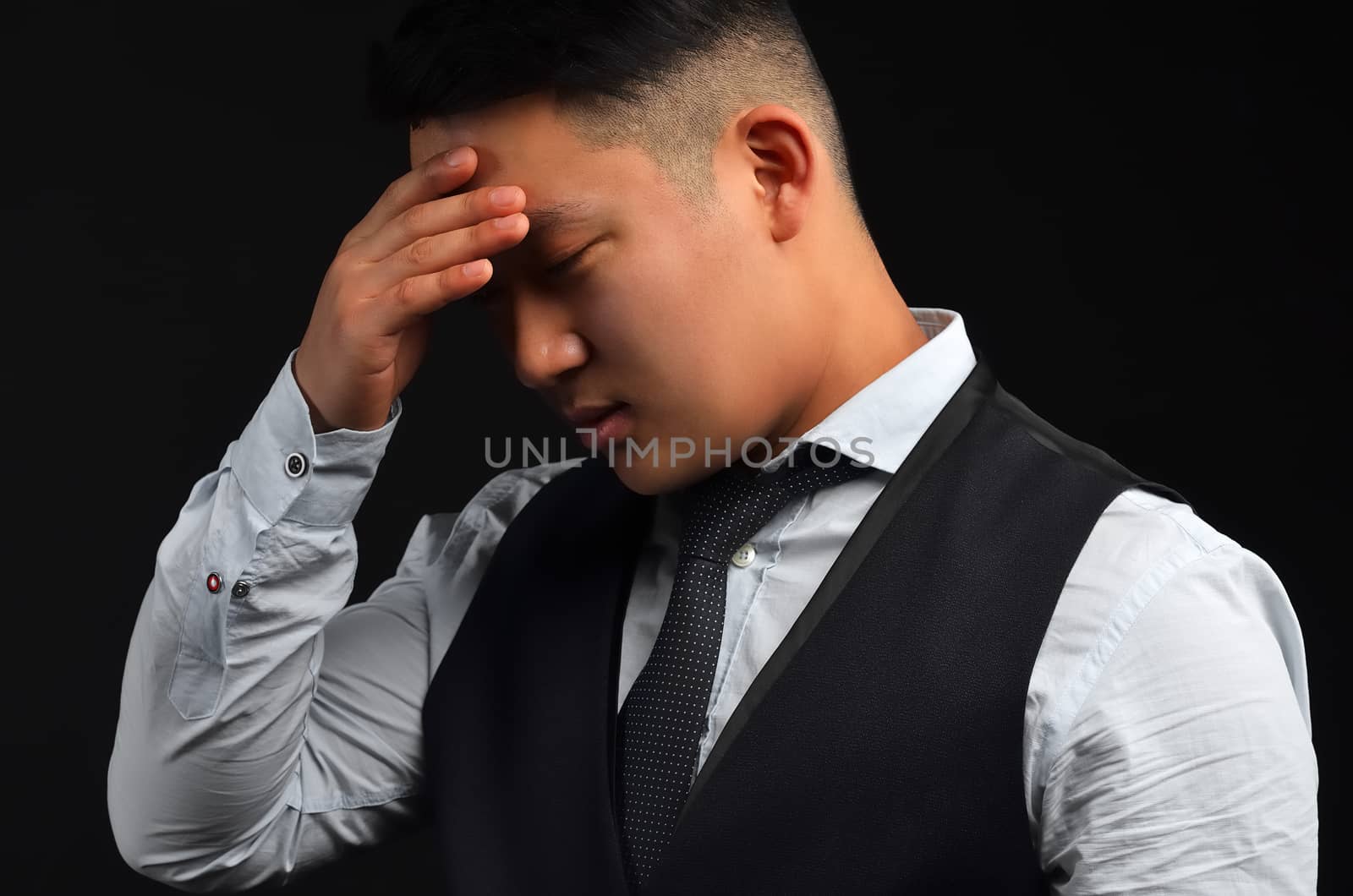 A thoughtful Asian man, put his hand to his head, as if he had a headache