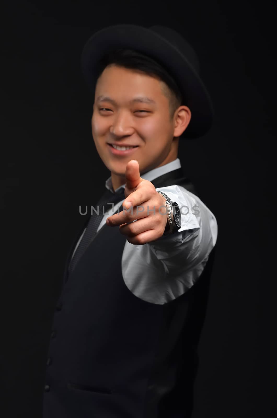 A smiling young Asian man looks at the camera and shows his finger