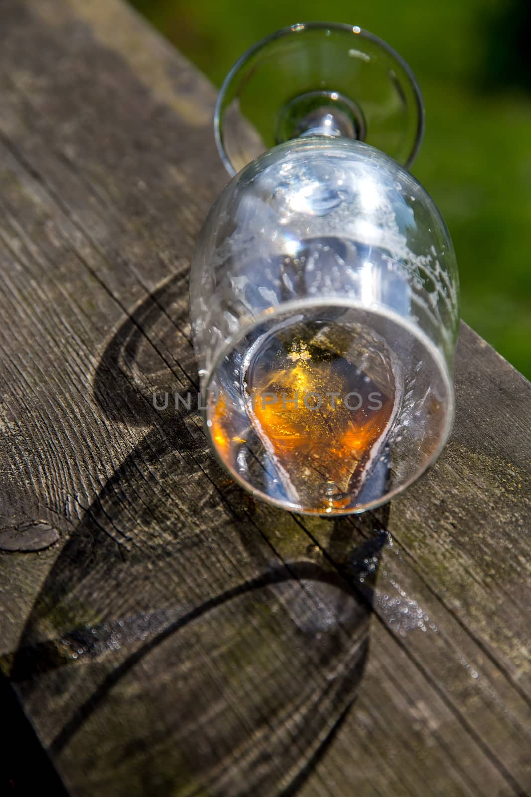 Overturned glass of beer on wooden table. Beer is an alcoholic drink made from yeast-fermented malt flavoured with hops. Overturned beer glass. 

