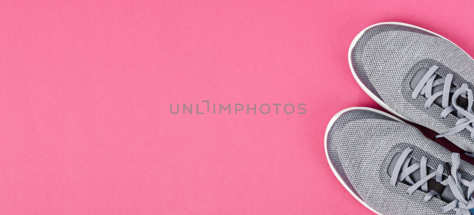 Grey sneakers on pink background. by Gamjai