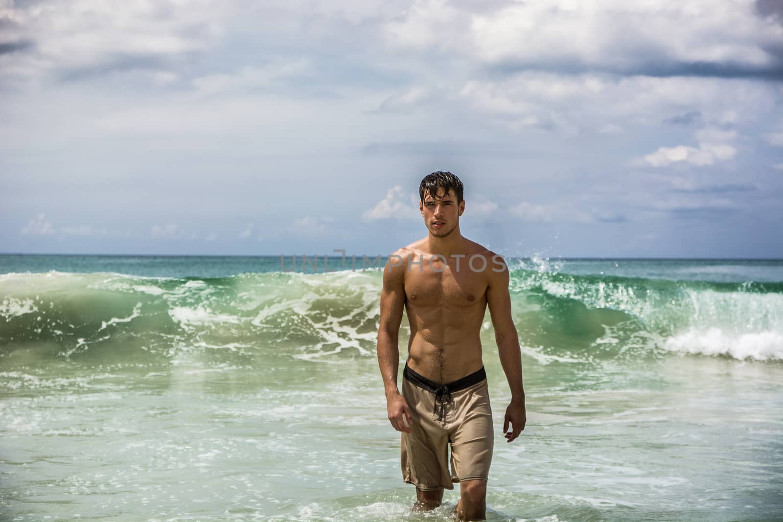 Handsome young man standing on a beach in Phuket Island, Thailand, shirtless wearing boxer shorts, showing muscular fit body