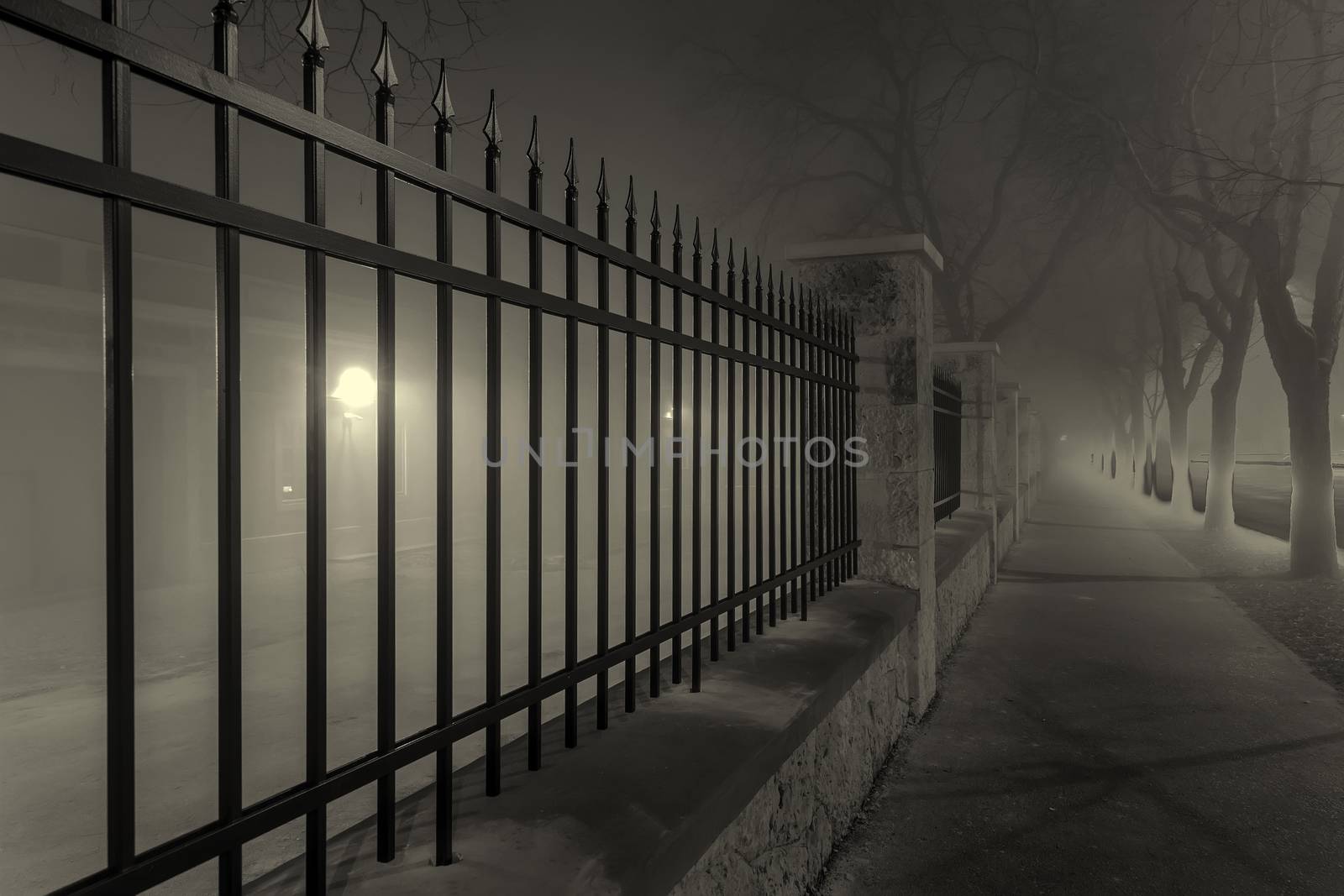 black fence along foggy city pavement