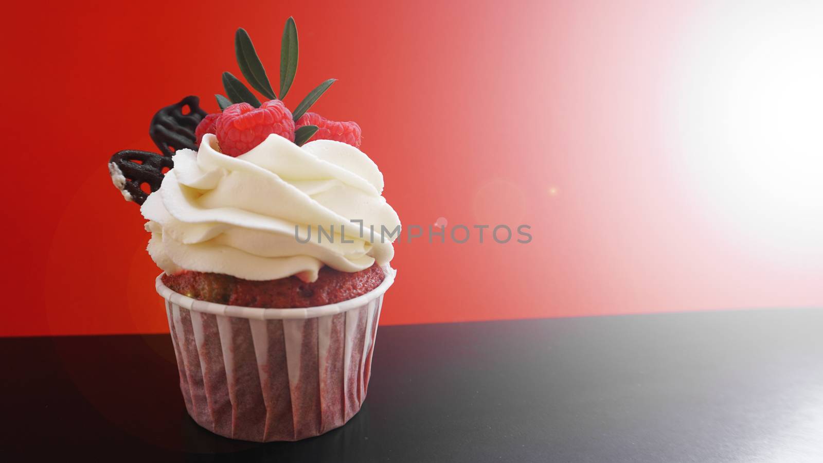 Delicious raspberry cupcakes on dark black and red background - Handmade Sweet dessert, cupcake with butter cream and raspberry