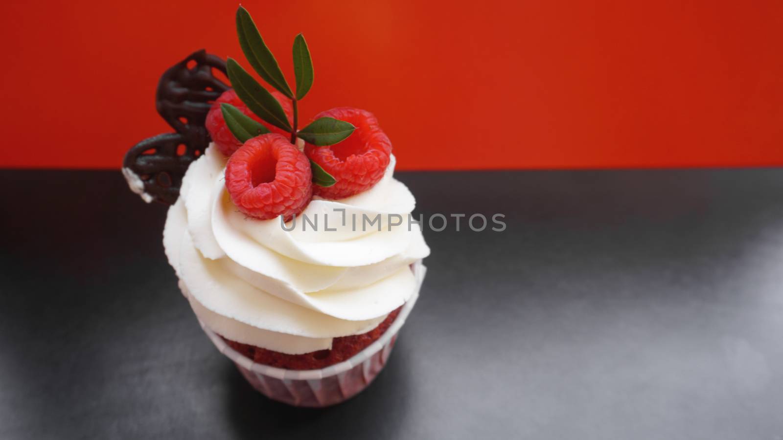 Delicious raspberry cupcakes on dark black and red background - Handmade Sweet dessert, cupcake with butter cream and raspberry