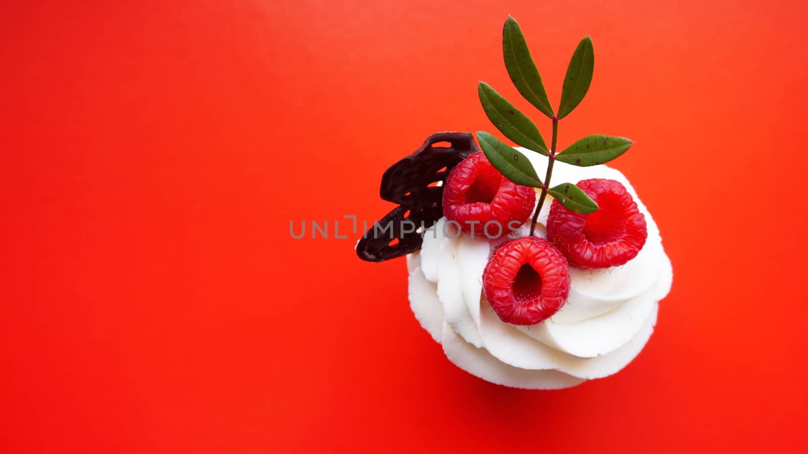 Handmade Sweet dessert, cupcake with butter cream and raspberry on red background