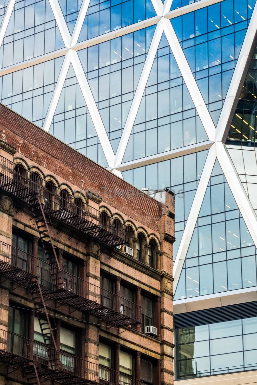 Contrast of old brick building and modern skyscraper with glass  by MXW_Stock