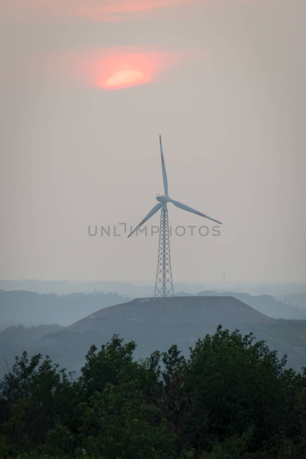 Wind turbine with tower made by steel frame construction sunset