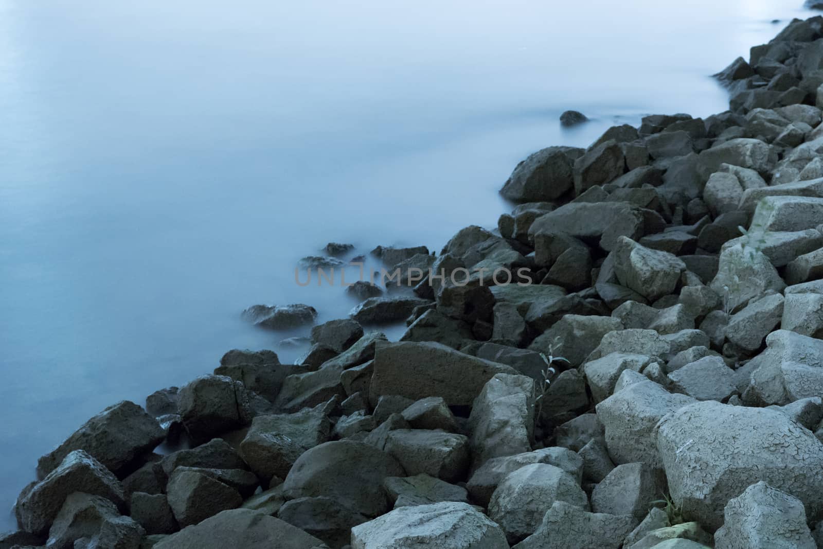 Long exposure of stones at water at river side by MXW_Stock