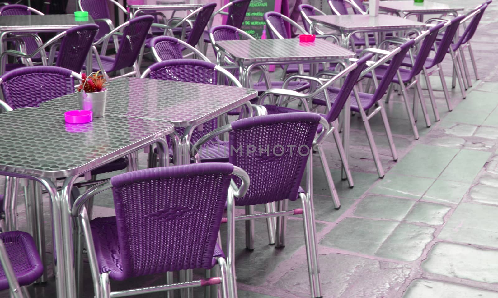 Empty European street cafe with purple chairs and tables, selective focus.