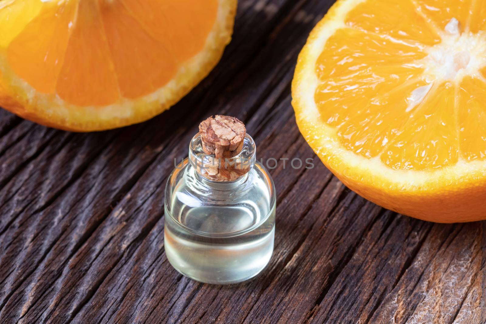 A bottle of orange essential oil with fresh oranges by madeleine_steinbach