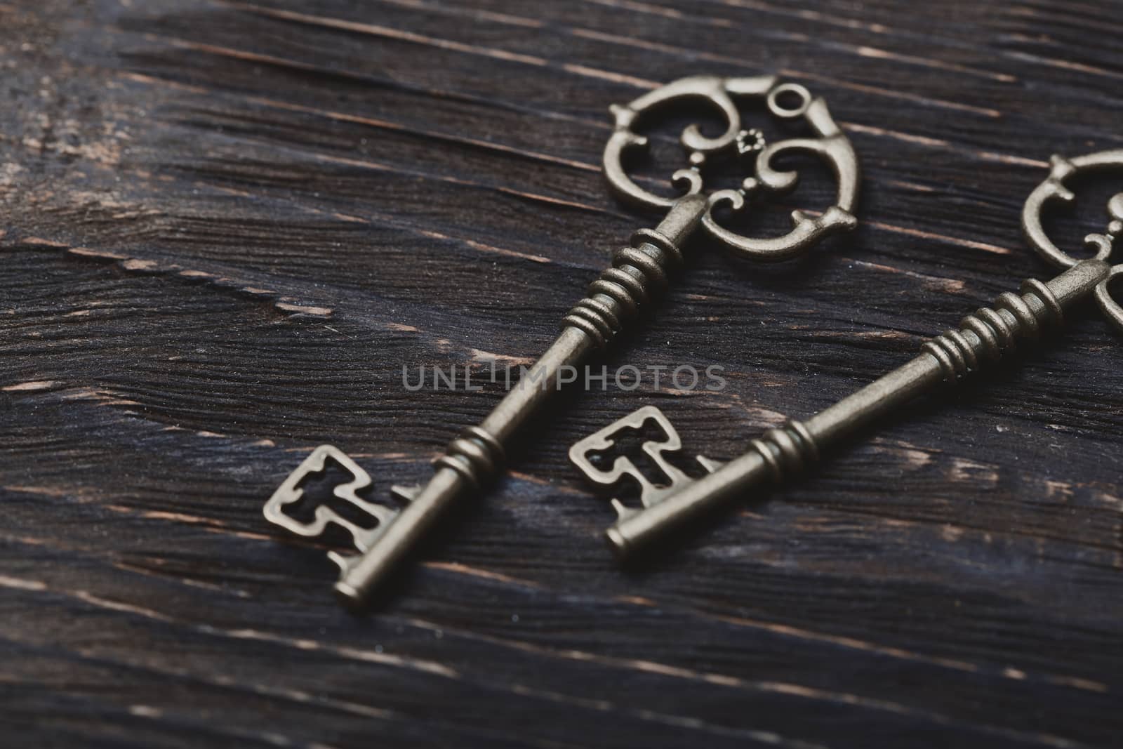 Two vintage bronze keys on a wooden table by Novic