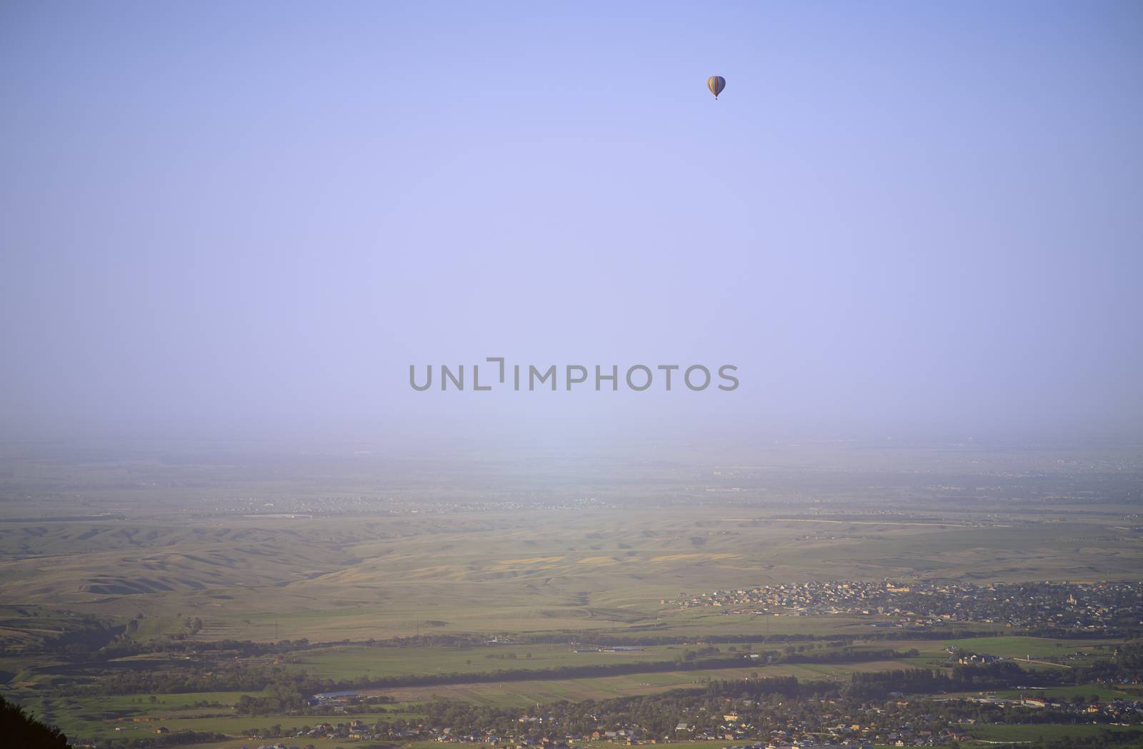 Hot air balloon above the green field and villages