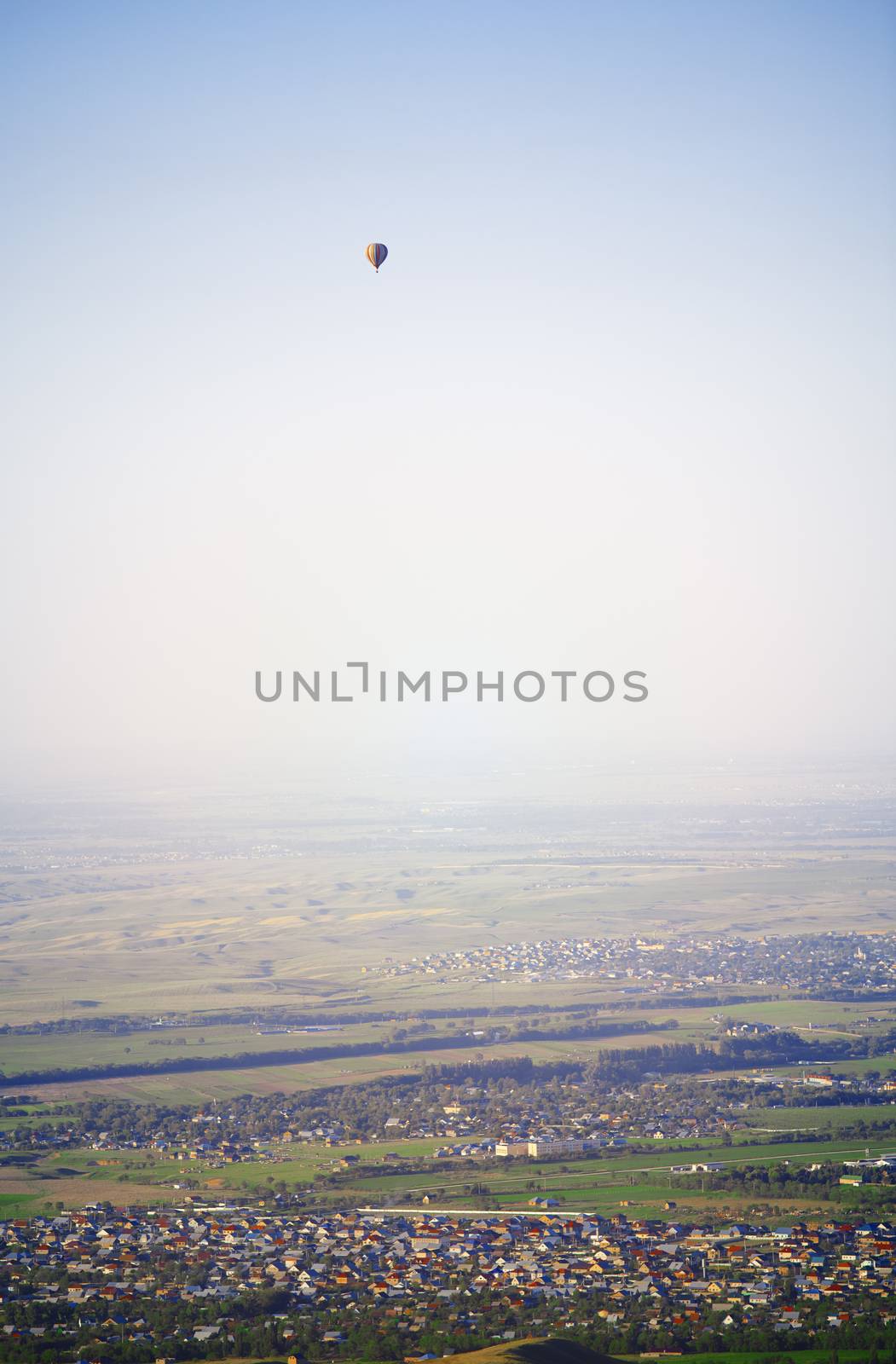 Hot air balloon above the green field and villages
