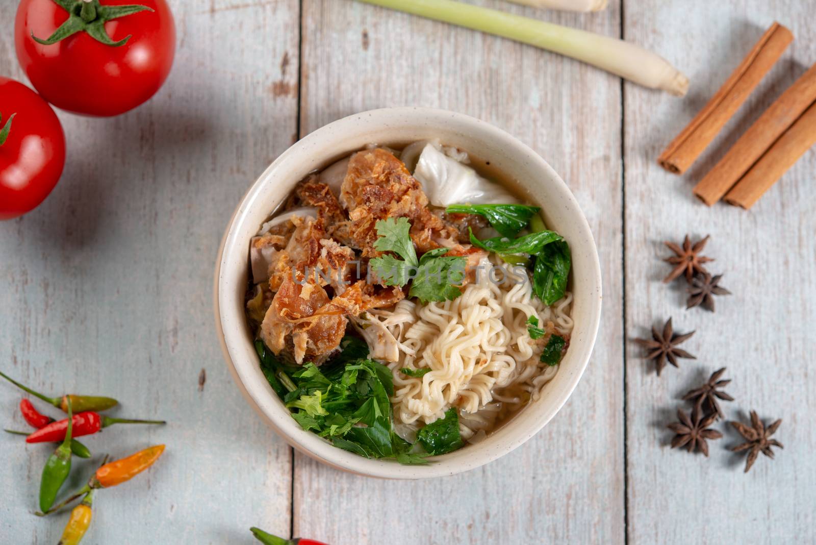 Asian ramen noodles soup with vegetables and chicken in bowl. Top view flat lay on wooden background.