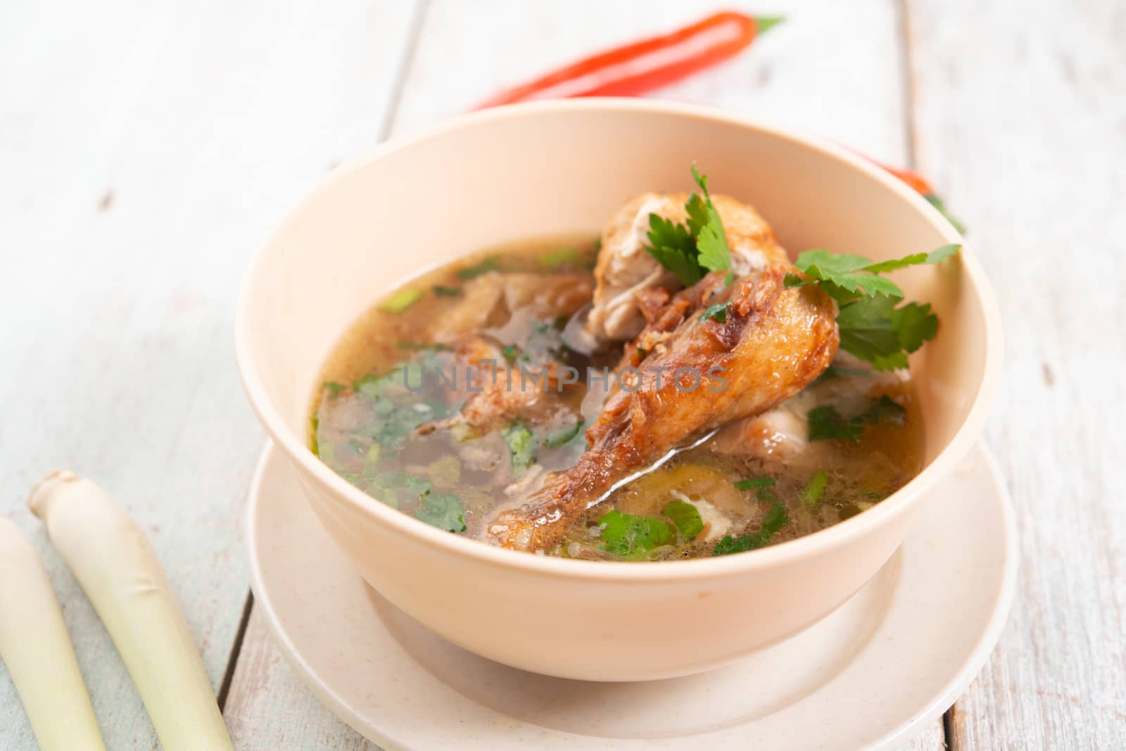 Asian style chicken soup in bowl, wooden background. 