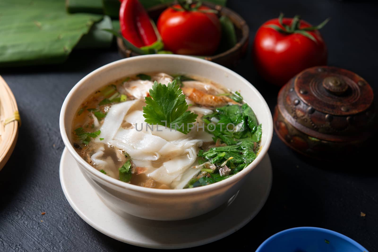Asian kway teow soup noodle and chicken in bowl on dark background. 