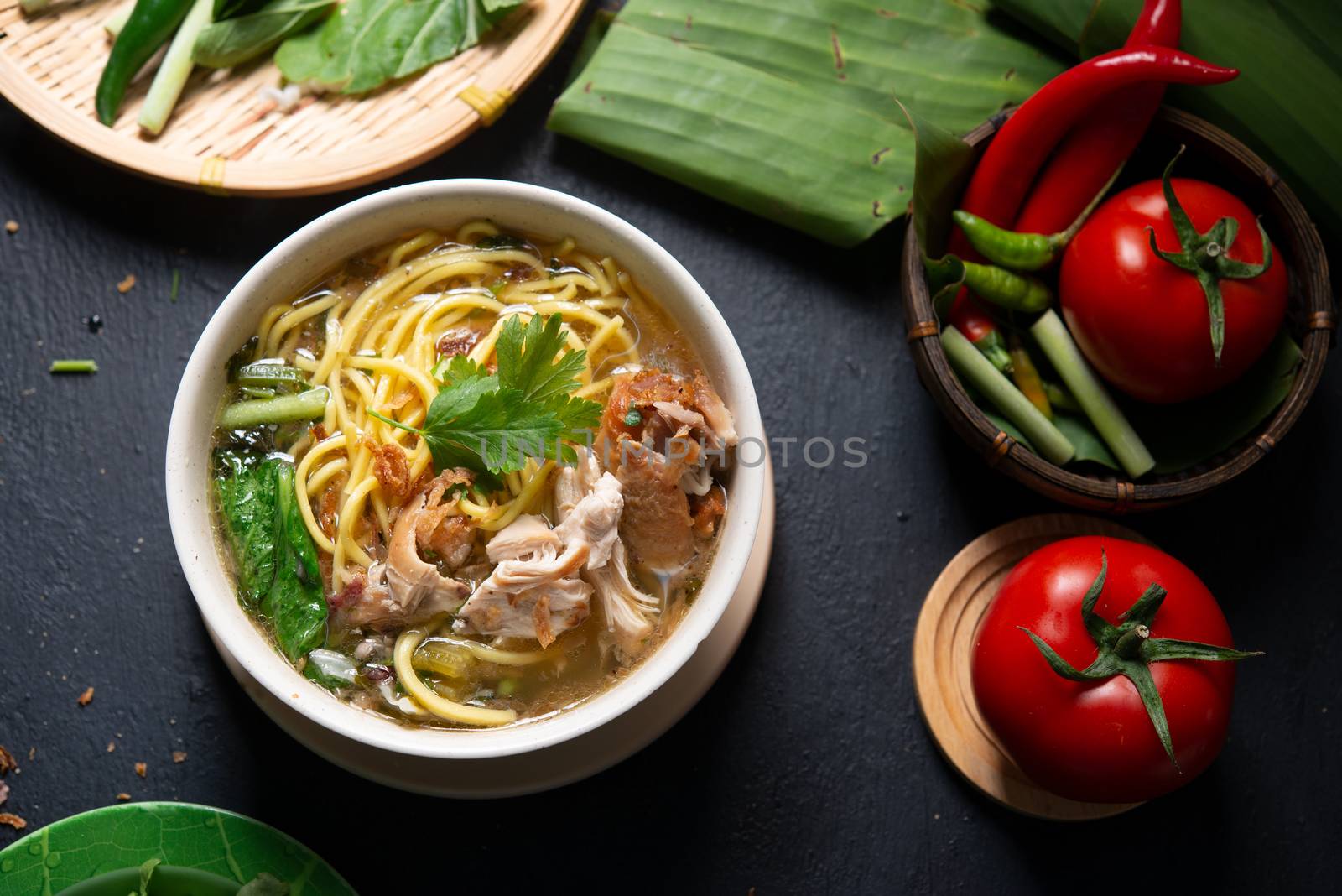 Asian soup noodles and chicken in bowl on dark background. Top view flat lay.