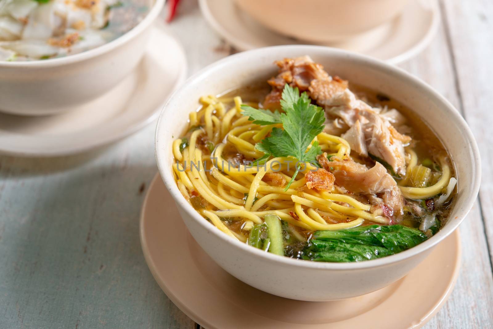 Asian soup noodles and chicken in bowl on wooden background. 