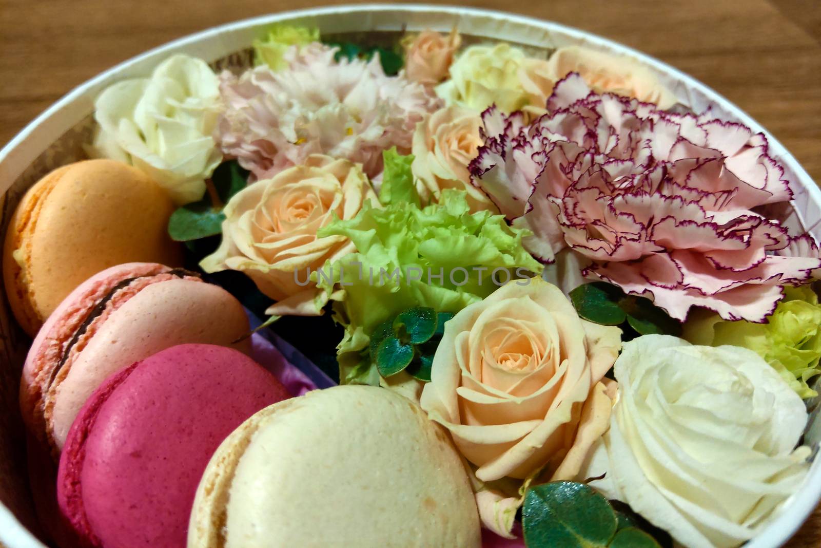 Colorful macaroons and flowers. Sweet macarons in gift box. Top view