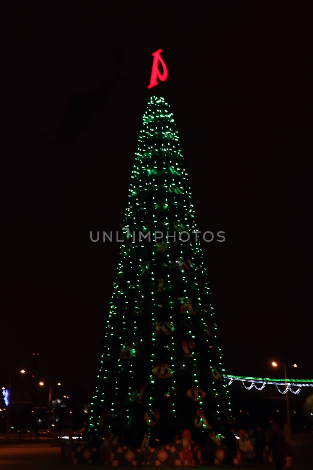 Christmas tree with lights on, in front of a city landscape at night. by kip02kas