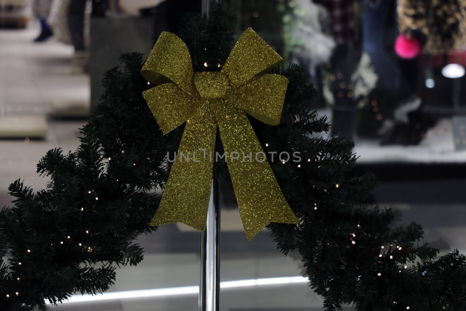 Yellow shiny bow and Christmas tree branch lies on gray background. by kip02kas