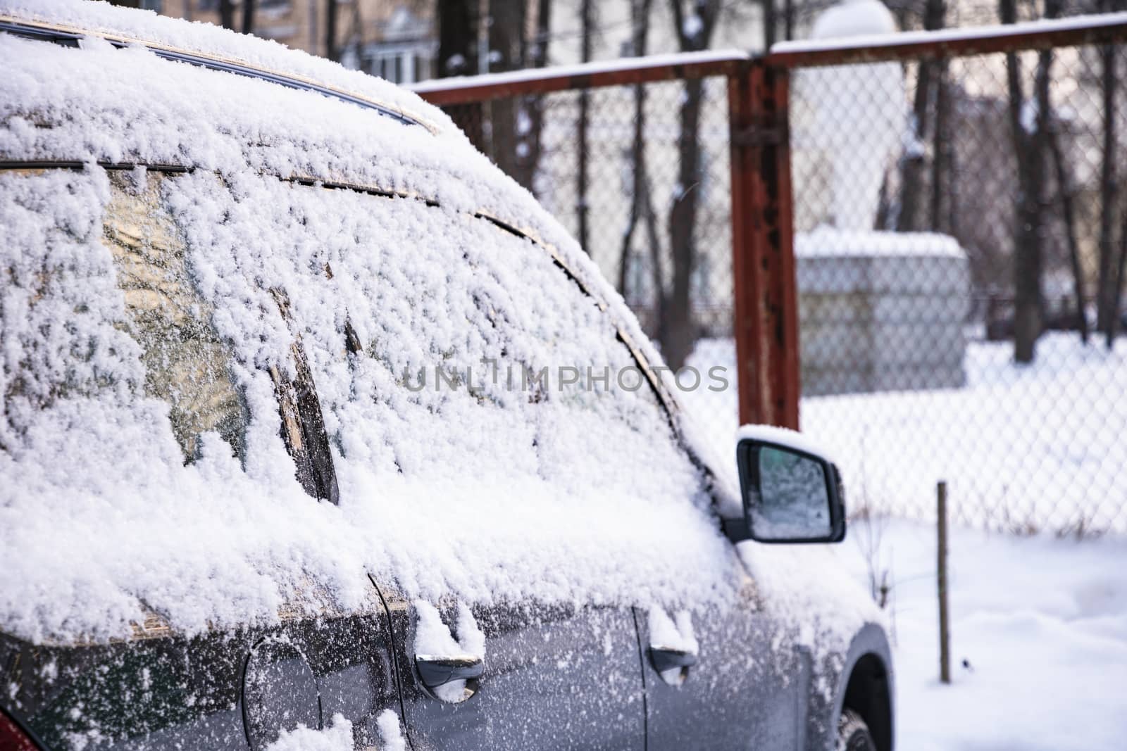 Snow covered ows of cars in the parking lot. Urban scene, snowstorm. Clean automobile from the snow. by kip02kas