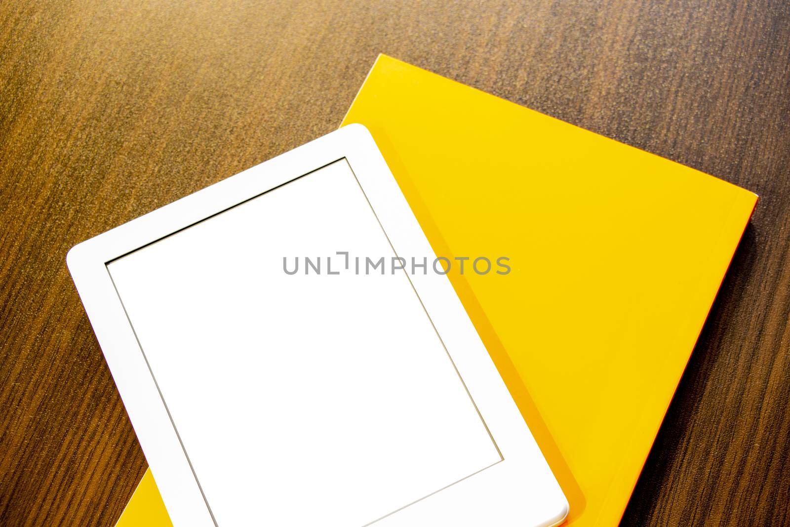 On the table is a portable e-book and paper book. by kip02kas