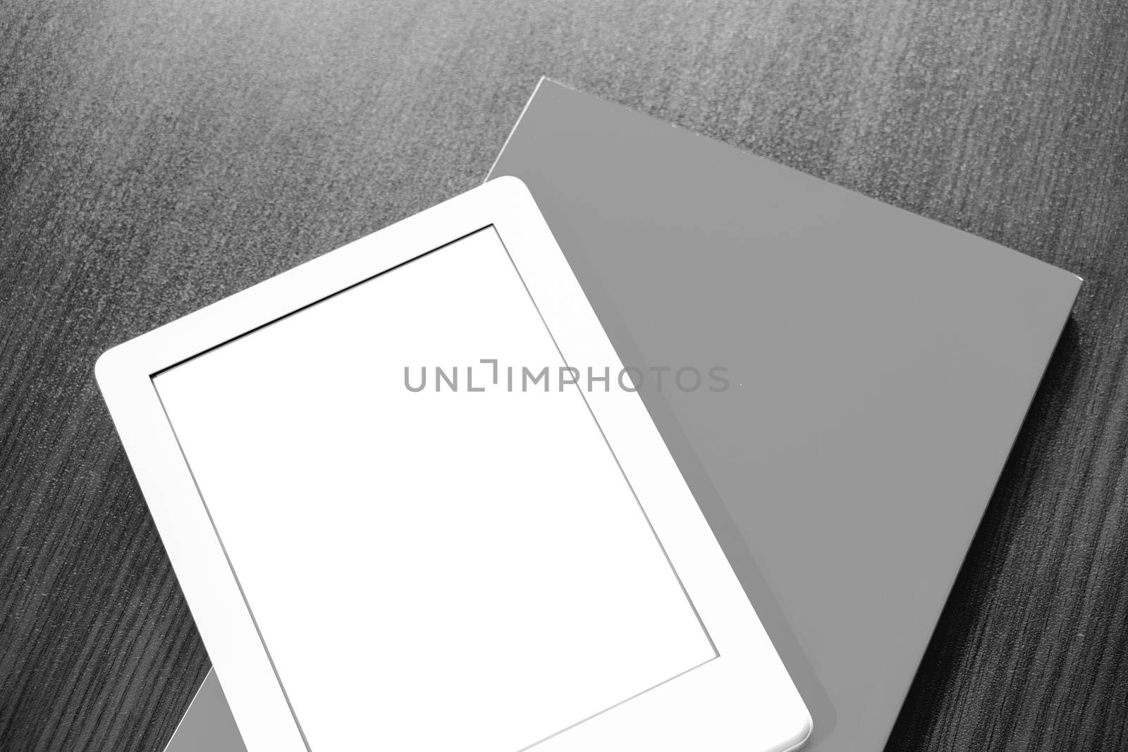 On the table is a portable e-book and paper book