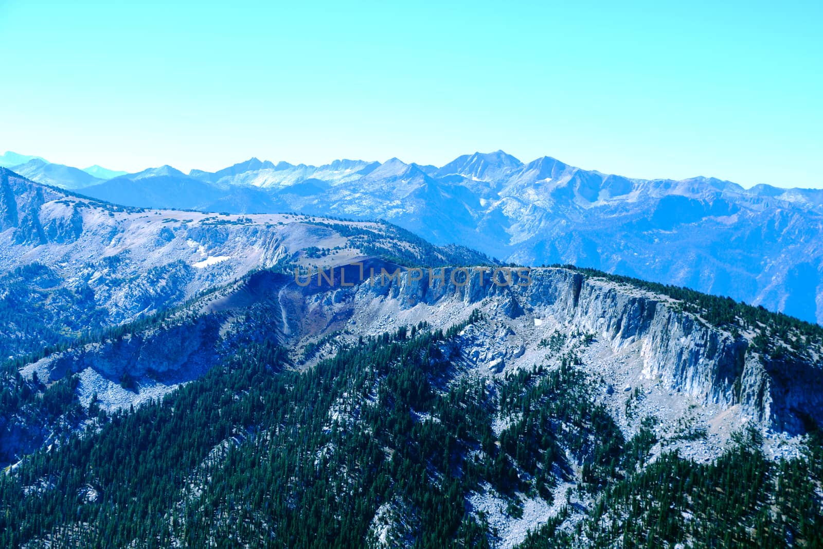 View from the top of the mountain or Olympus to the peaks on the background of clouds and blue sky.