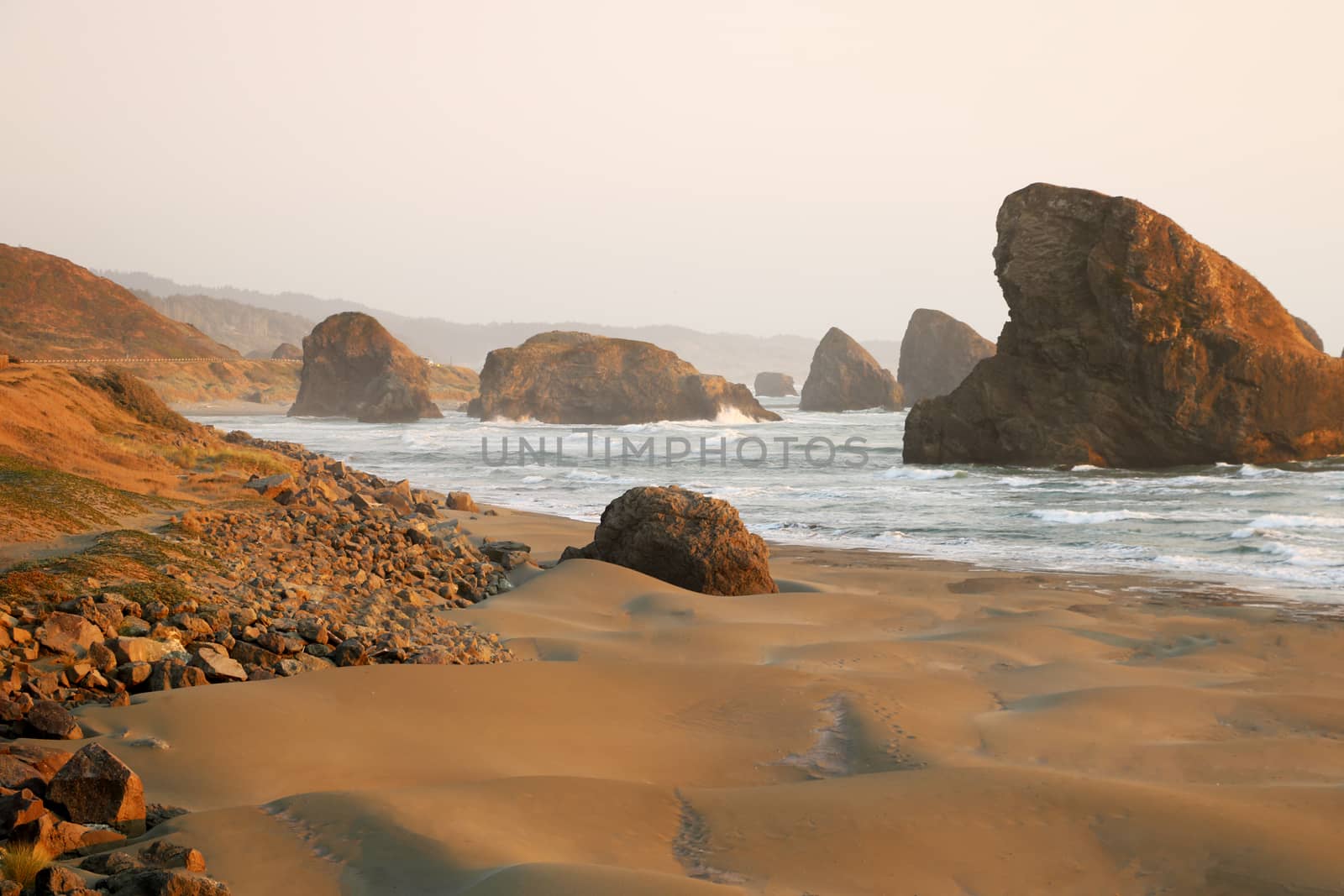 View of the sandy beach and rocks during sunset in the Pacific Ocean.