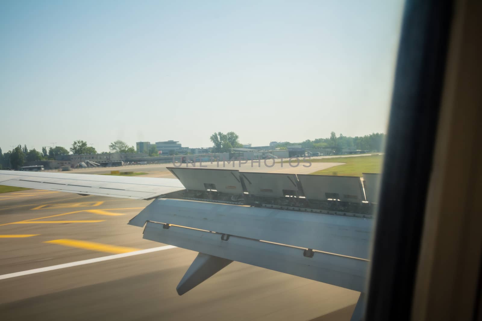 Airplane wing during landing with flaps down on the runway.