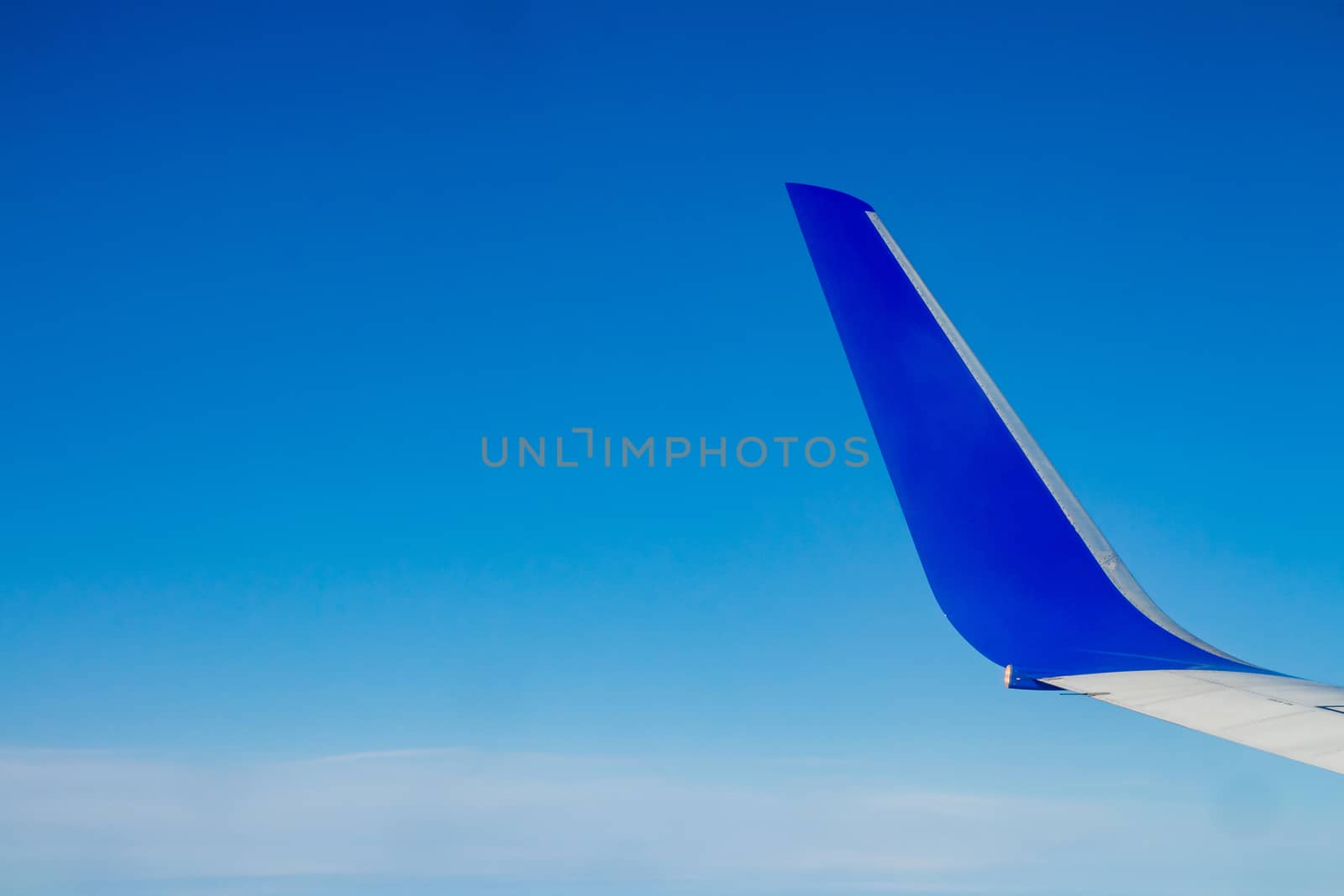 Airplane wing on the blue sky with clouds.