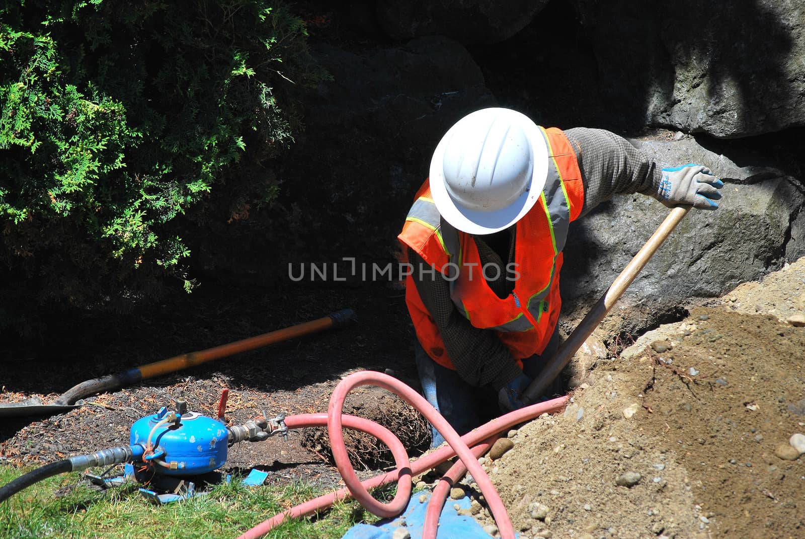 Utility worker repairing a broken water pipe underground.