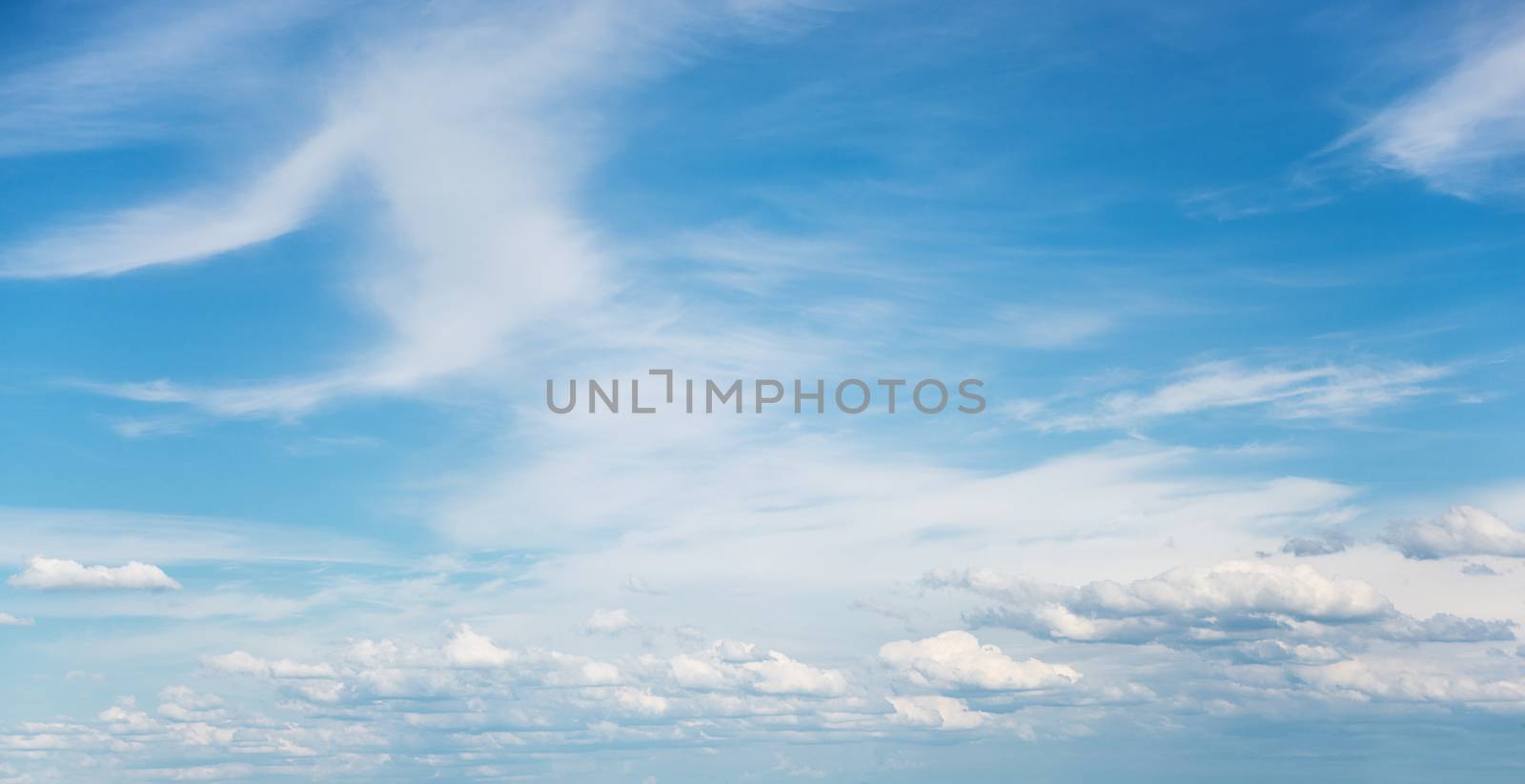Panorama of vast blue summer sky with fluffy white cumulus and cirrus clouds