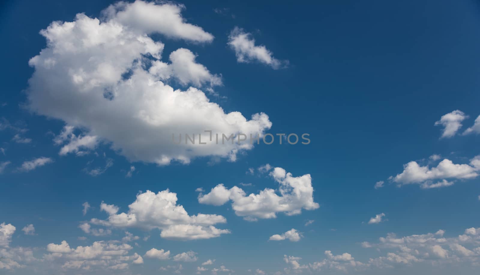 Panorama of vast blue summer sky with fluffy white cumulus clouds