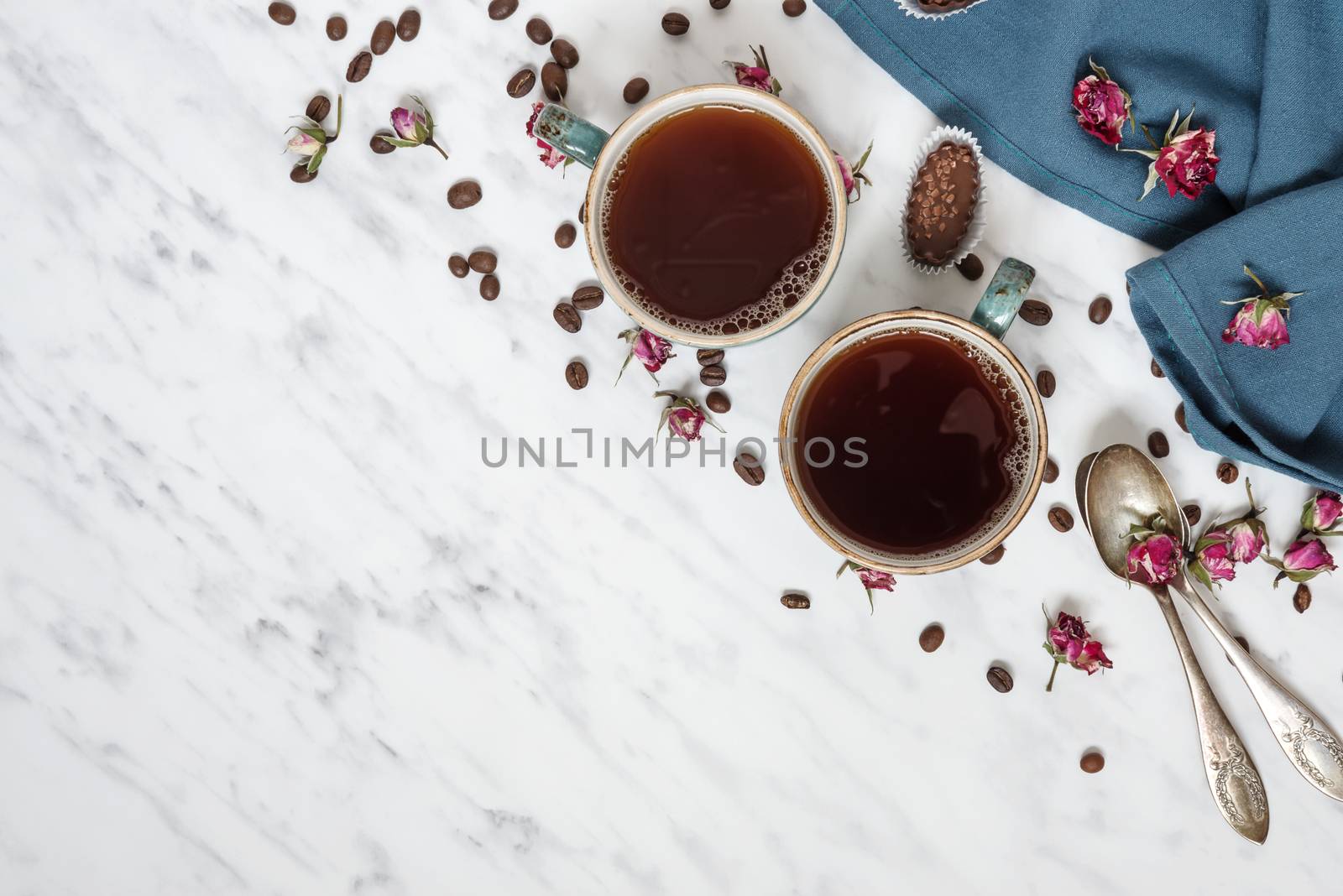 Morning composition with a cup of black coffee, chocolate candies and blue linen napkin on a marble surface with space for text, top view