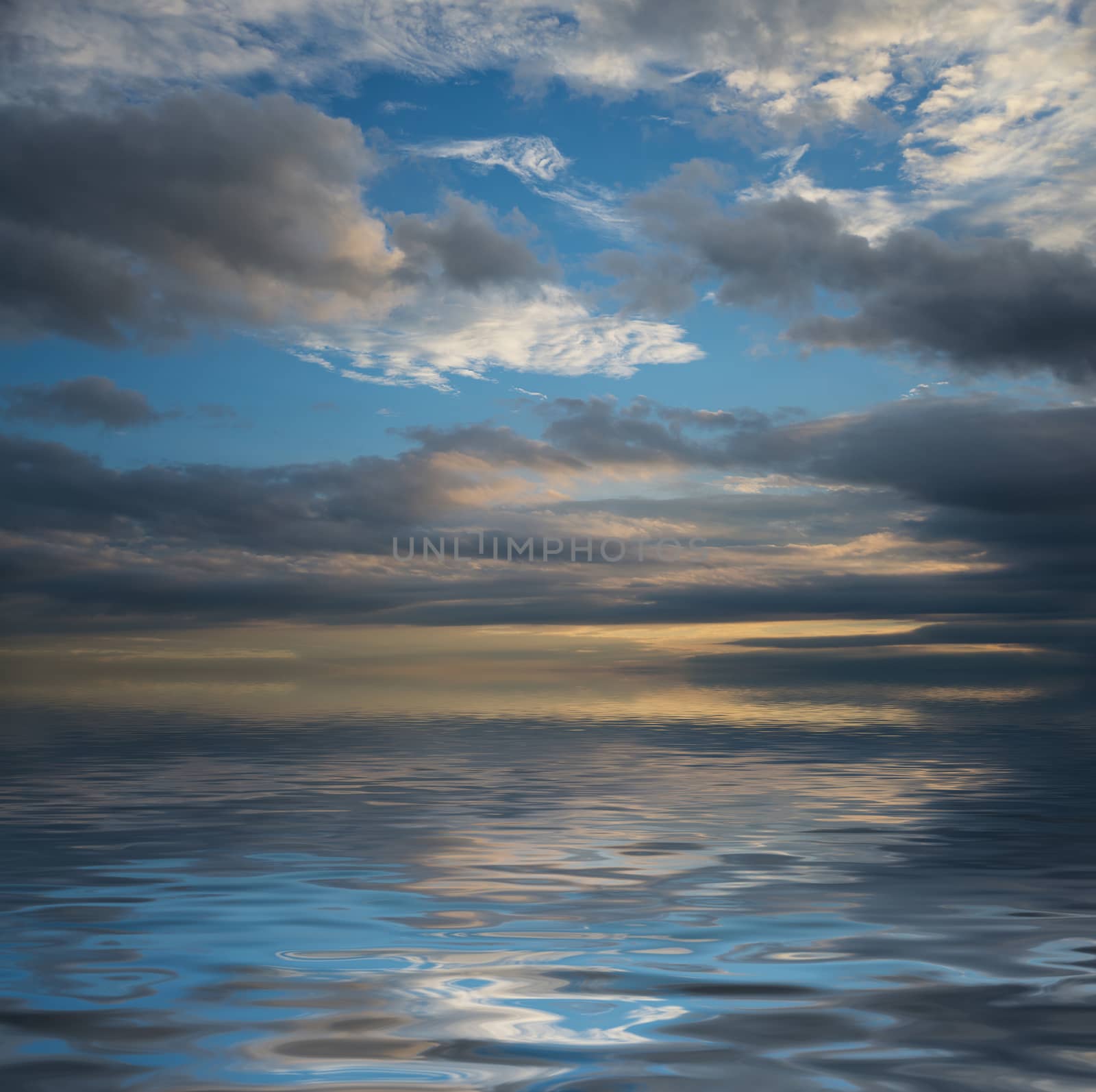 Beautiful seascape with dramatic sunset sky with dark clouds reflected in a water surface with small waves