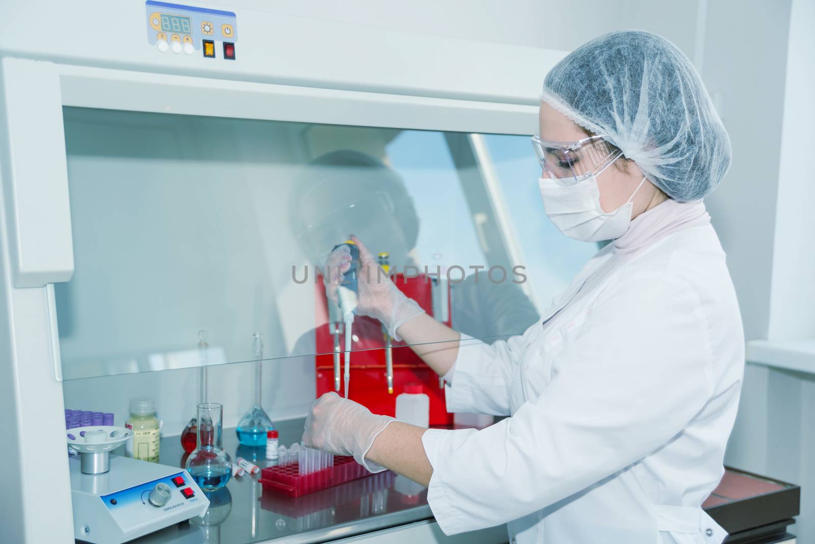 Woman scientist in a white protective clothing conducts research in a lab