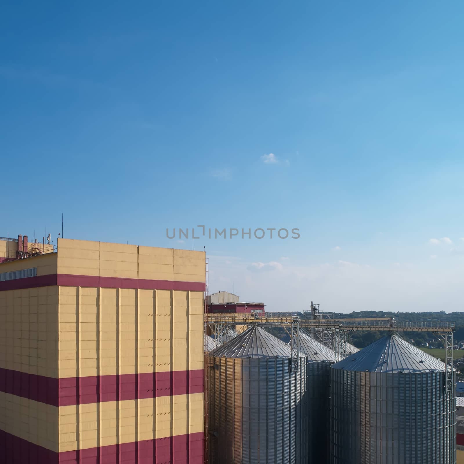 Agricultural Silo. Storage and drying of grains, wheat, corn, soy, against the blue sky with clouds