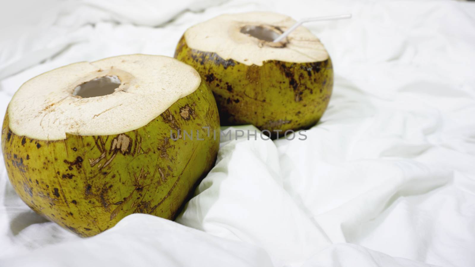 Fresh green coconut with straw ready to drinking on white fabric background