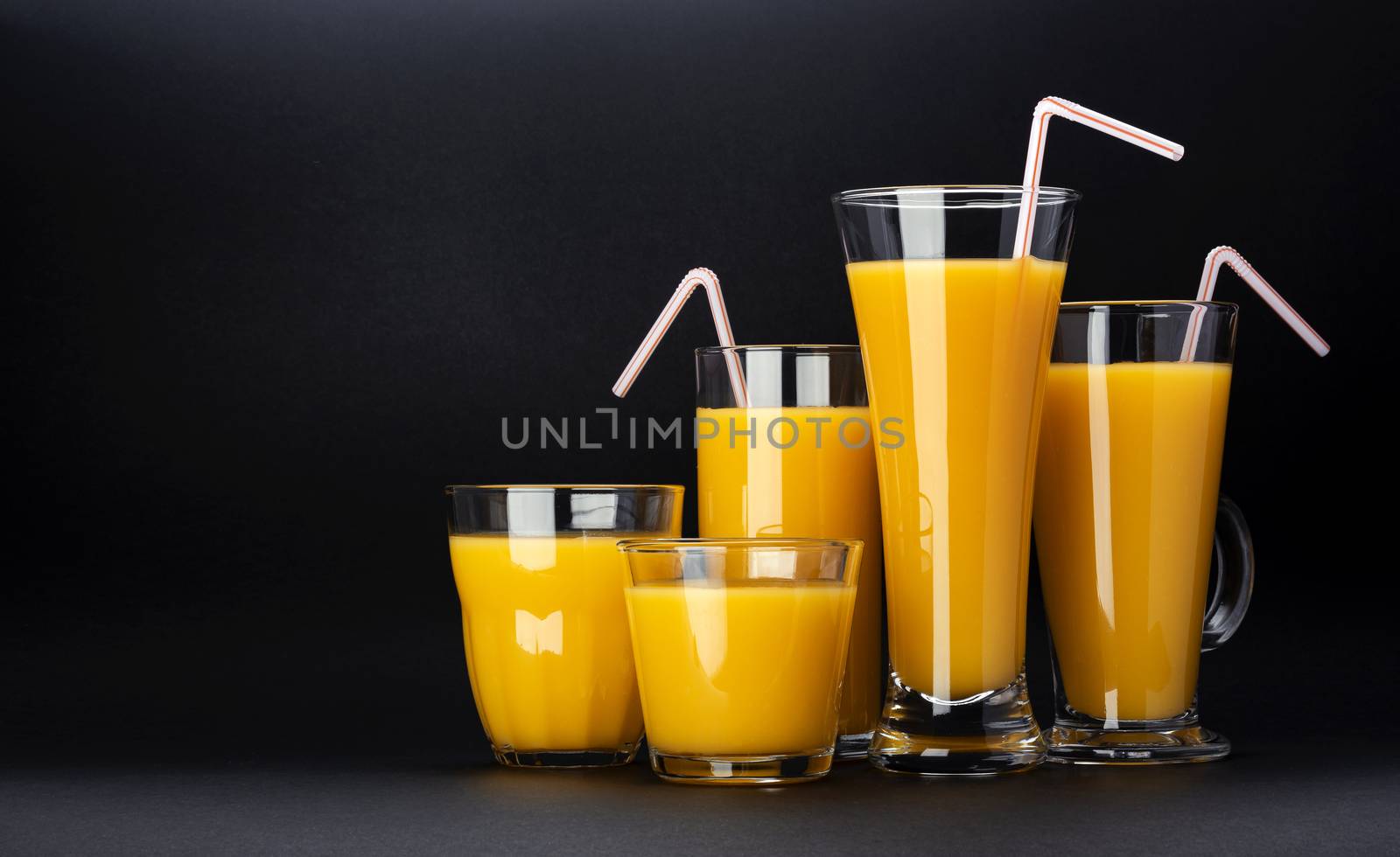 Glasses of orange juice on black background with copy space by xamtiw
