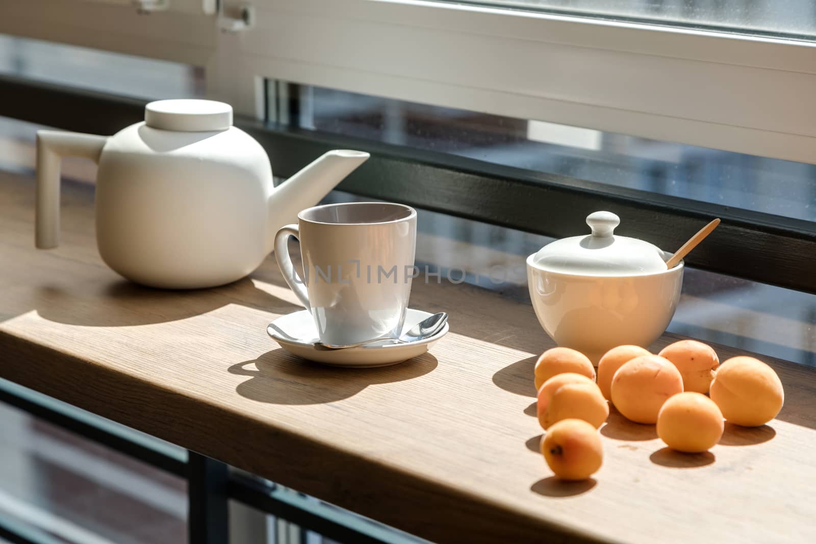 Ceramic teapot, mug and sugar bowl near apricots. by sveter