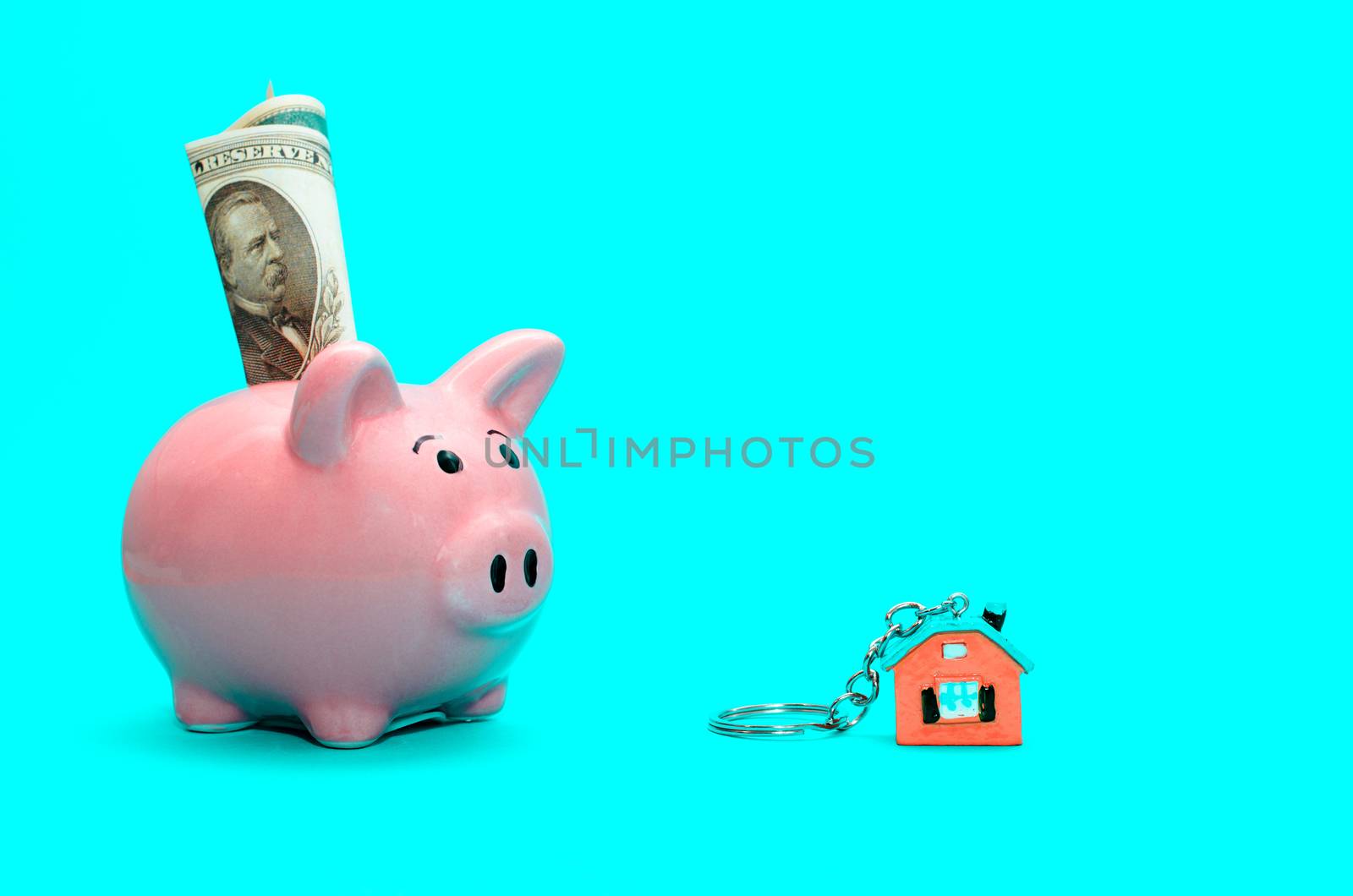 Pink piggy bank with a house on the table. Tinted. Concept of saving finances and real estate deposits